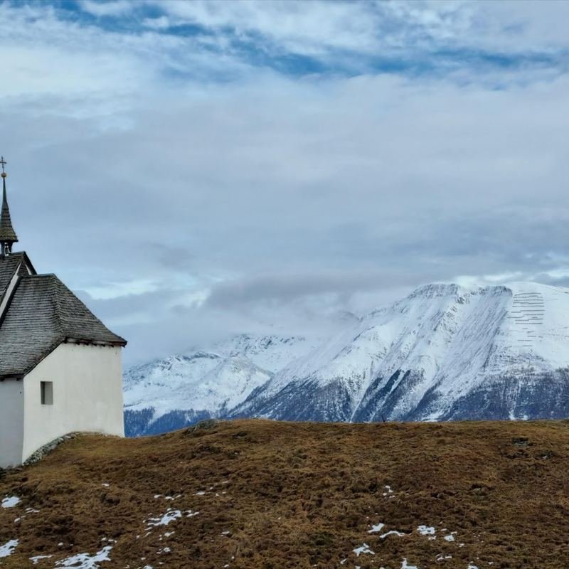Capilla alpina frente a una montaña nevada