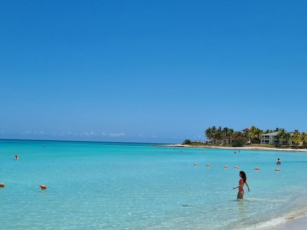 A white-sand beach and turquoise water with palm trees behind