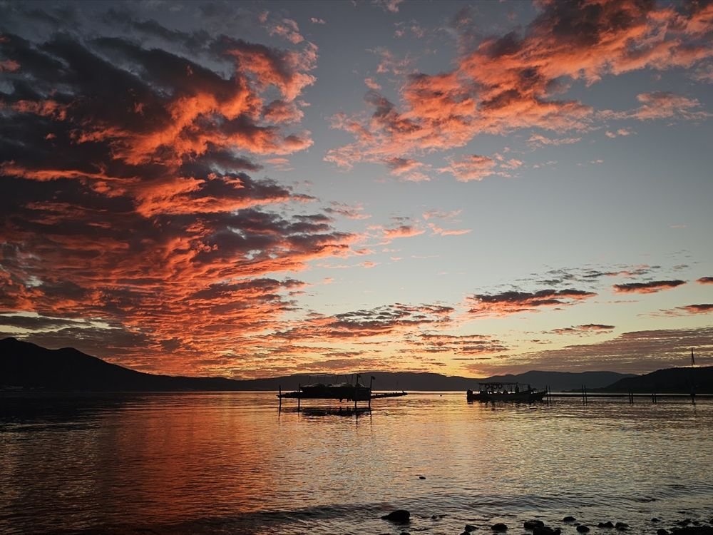 Sunset over the water with boats in silhouette
