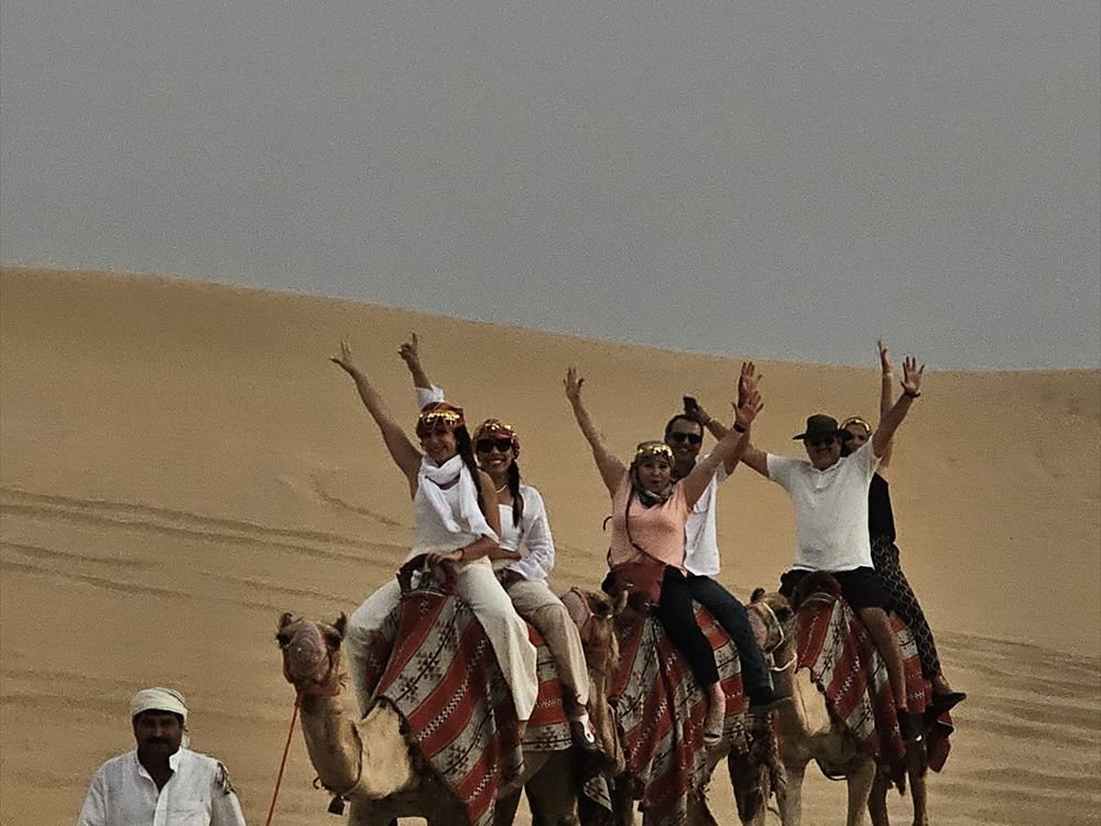 A group of travellers riding camels in the desert